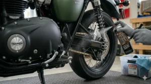 Protective anti-corrosion spray or chain wax being applied to a motorcycle's drive chain and rear components, highlighting preventative maintenance routines and motorcycle winter storage products.