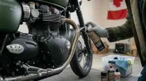 An anti-corrosion rust inhibitor spray being applied directly to a motorcycle engine casing, showcasing defensive motorcycle winter storage products used before long-term storage in damp conditions.