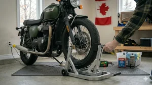 A rider securing a motorbike's front tire into an adjustable metal wheel chock stand, symbolizing a secure and complete setup with essential motorcycle winter storage products in a Canadian home garage.