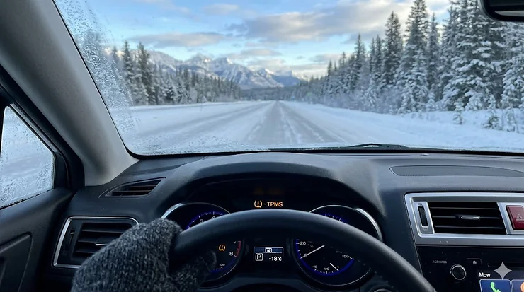 Low tire pressure warning light illuminated on a car dashboard during a freezing Canadian winter day with snow outside.