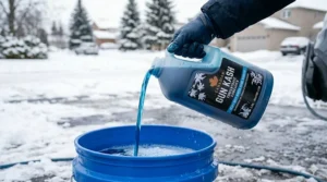 Pouring concentrated heavy duty car wash soap into a bucket.