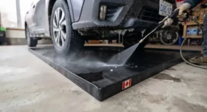 Close-up of oil and water containment mat capturing vehicle fluid leaks. – Tapis de protection retenant les fuites de liquides du véhicule.